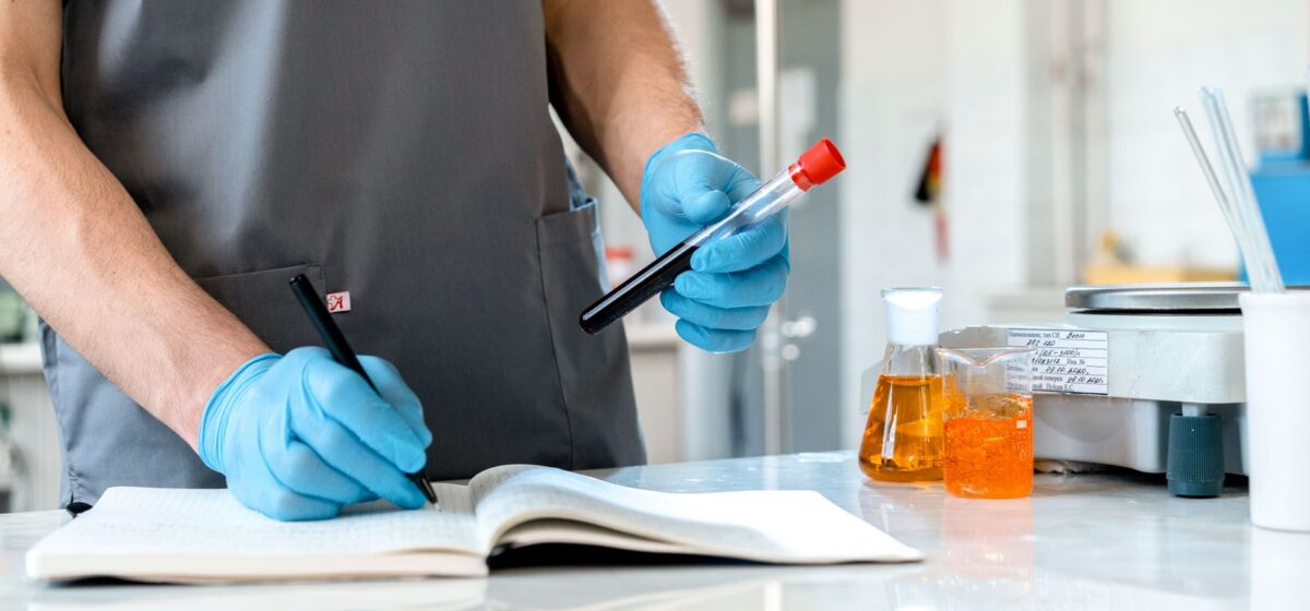 Researcher recording lab observations in a notebook